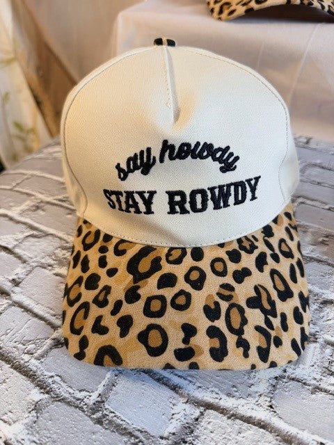 Cap with leopard print brim and 'say howdy STAY ROWDY' text on a textured surface.