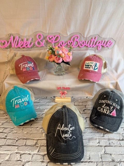 Collection of hats with various designs and text on a table with 'Nikki & Co Boutique' sign.