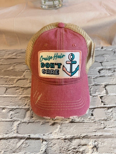 Red cap with 'Cruise Hair Don't Care' patch on a stone surface