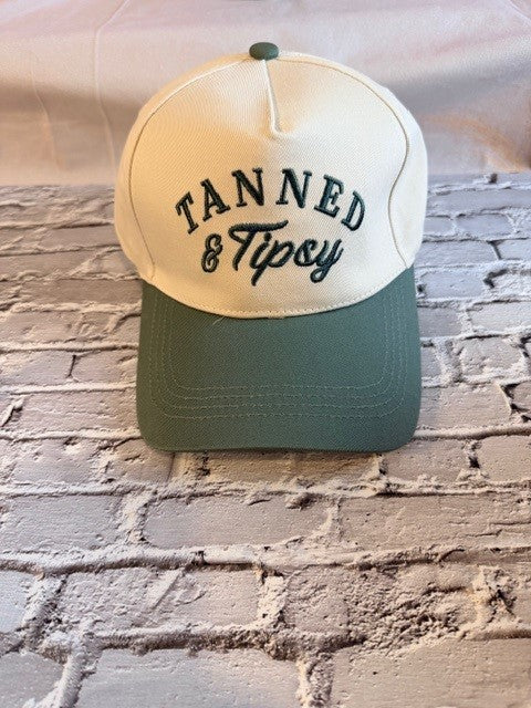 Cap with 'Tanned & Tipsy' text on a brick wall background