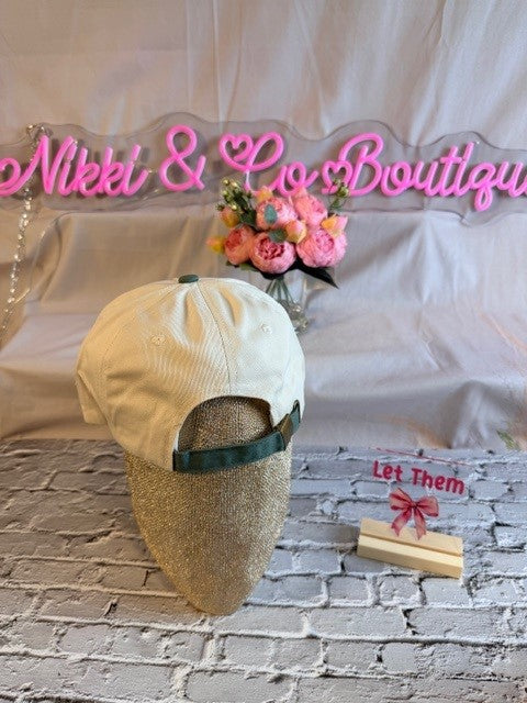 Decorative headboard with 'Nikki & Co Boutique' text, flowers, and a cap on a textured surface.