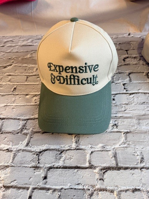 Cap with 'Expensive & Difficult' text on a brick wall background