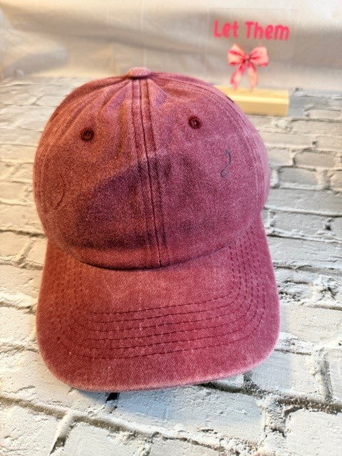 Maroon baseball cap on a textured surface with text overlay