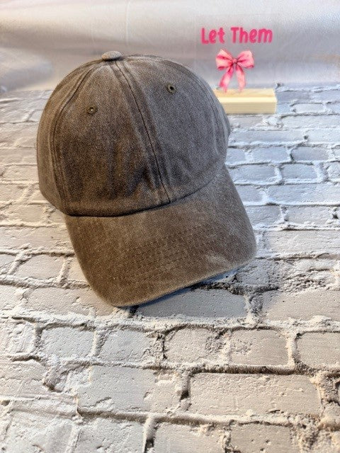Brown baseball cap on a brick surface with 'Let Them' text in pink above.