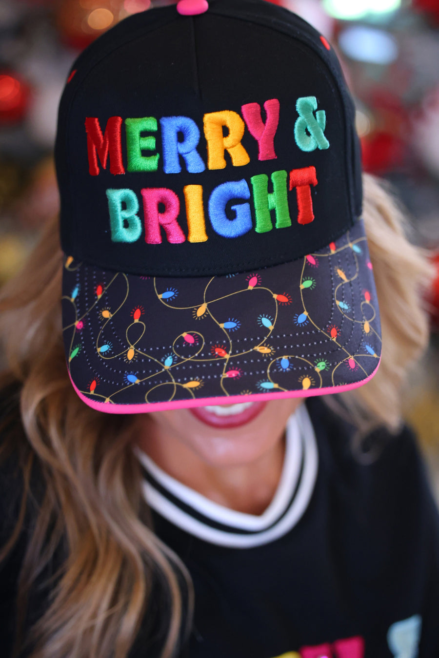 A person wearing a black baseball cap with colorful embroidered &