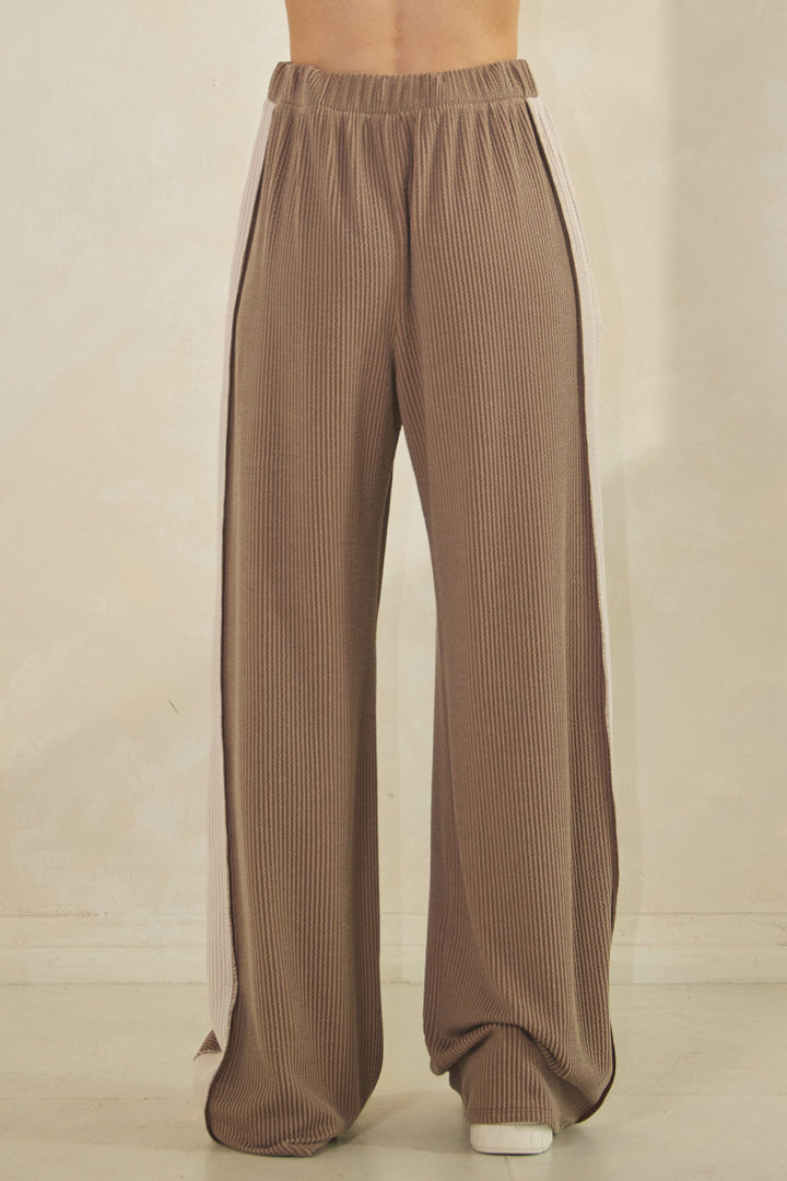 Woman wearing taupe ribbed pants with a cream-colored strip down the sides