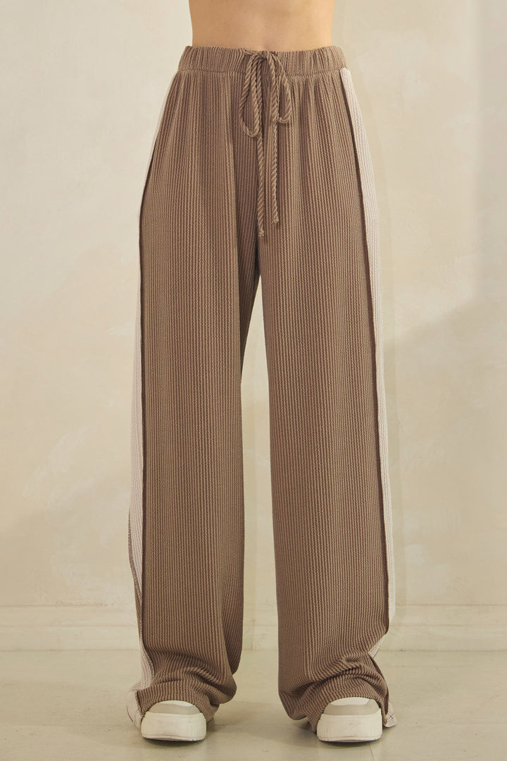 Woman wearing taupe ribbed pants with a cream-colored strip down the sides