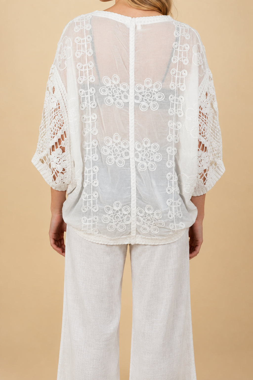 A woman wearing a crochet cardigan and pants.