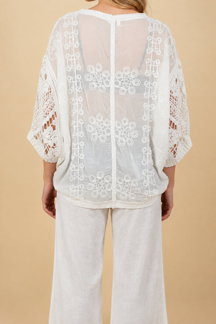A woman wearing a crochet cardigan and pants.