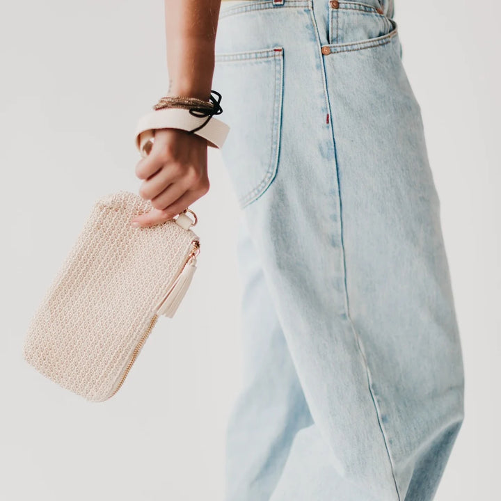 Person holding a cream-colored wristlet wallet