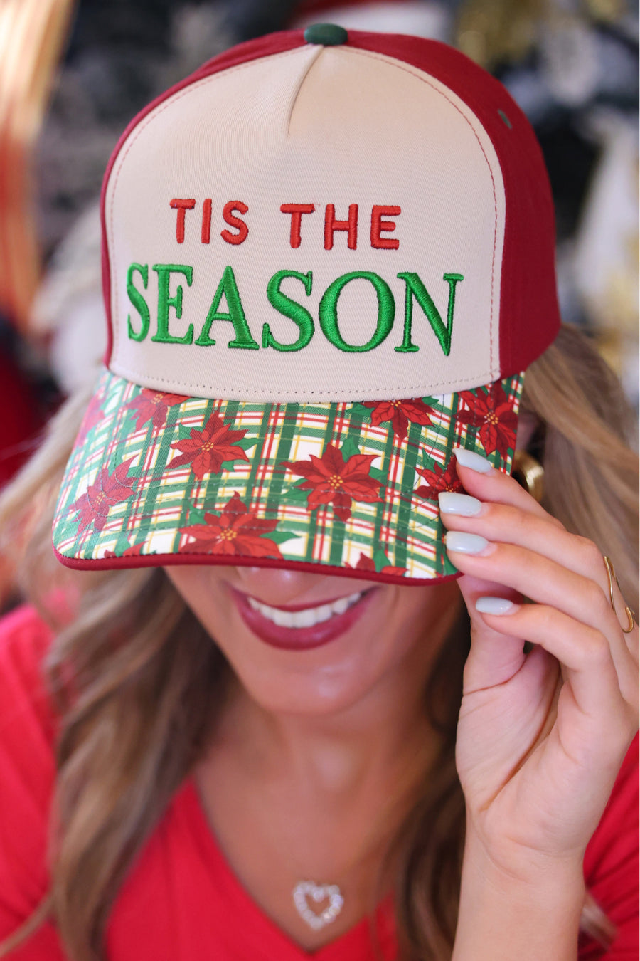 A woman wearing a red and beige baseball cap with &